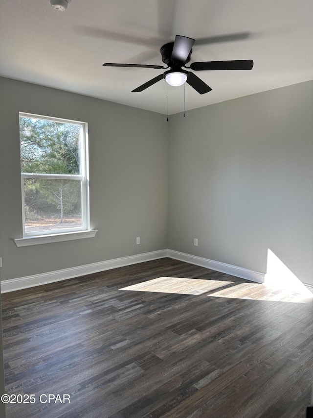 empty room featuring a ceiling fan, dark wood finished floors, and baseboards