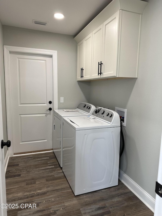 laundry area with dark wood-style floors, cabinet space, washing machine and clothes dryer, visible vents, and baseboards