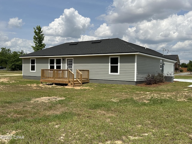 rear view of property with a lawn, a deck, and an attached garage