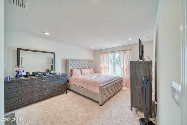 bedroom with light carpet and a textured ceiling