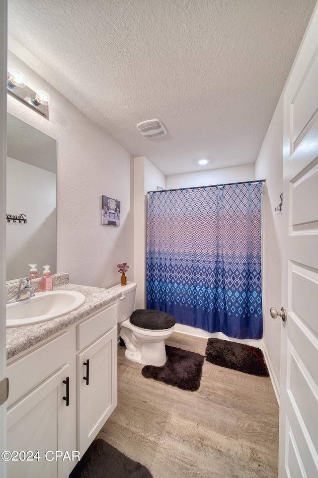 bathroom with toilet, a textured ceiling, vanity, curtained shower, and hardwood / wood-style flooring