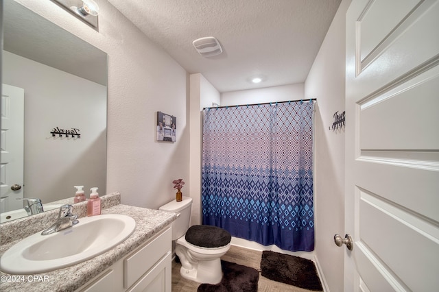 bathroom featuring walk in shower, vanity, toilet, and a textured ceiling