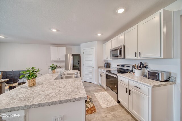 kitchen with white cabinets, light wood-type flooring, and stainless steel appliances