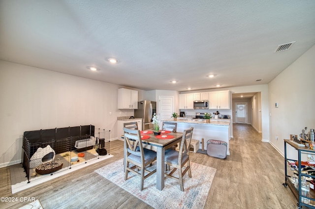 dining space with a textured ceiling and light wood-type flooring