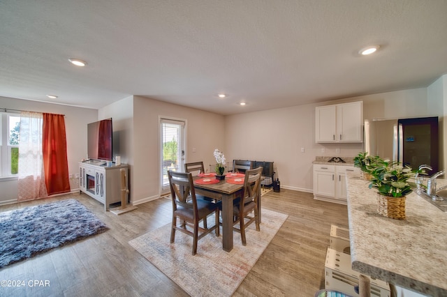 dining space with light hardwood / wood-style floors, a textured ceiling, and a wealth of natural light