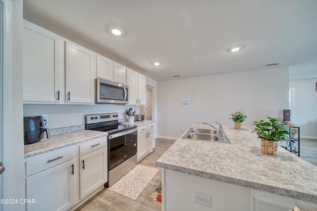 kitchen with sink, white cabinetry, a center island with sink, stainless steel appliances, and light hardwood / wood-style floors