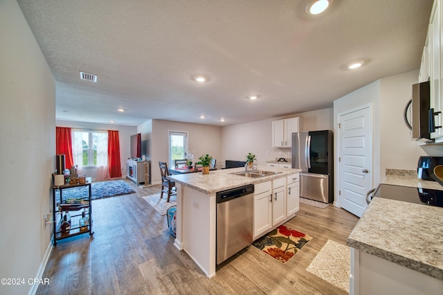 kitchen with a center island with sink, light hardwood / wood-style floors, white cabinets, and appliances with stainless steel finishes