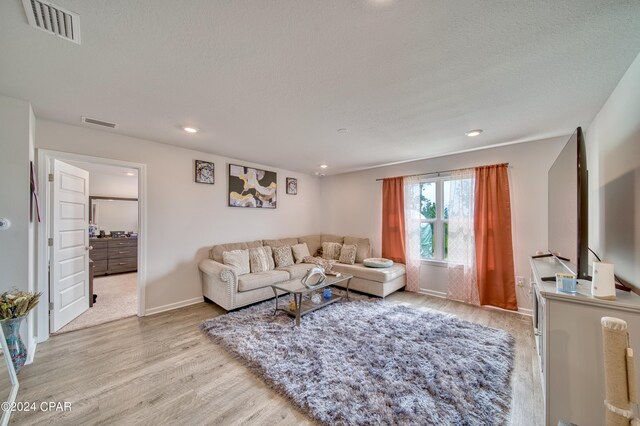 living room with light hardwood / wood-style flooring and a textured ceiling