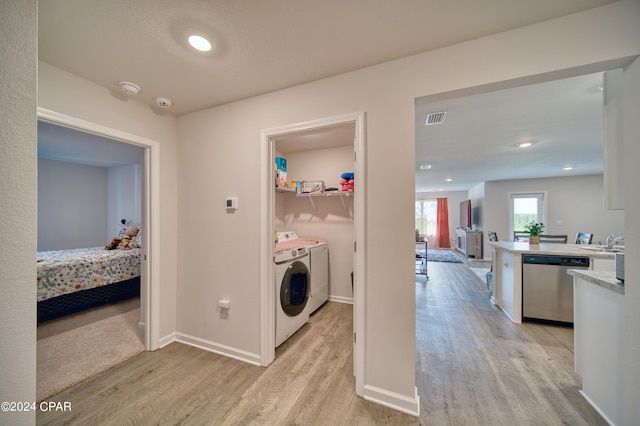 laundry room featuring sink, light hardwood / wood-style flooring, and independent washer and dryer