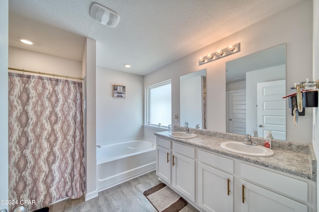 bathroom with wood-type flooring, shower with separate bathtub, vanity, and a textured ceiling