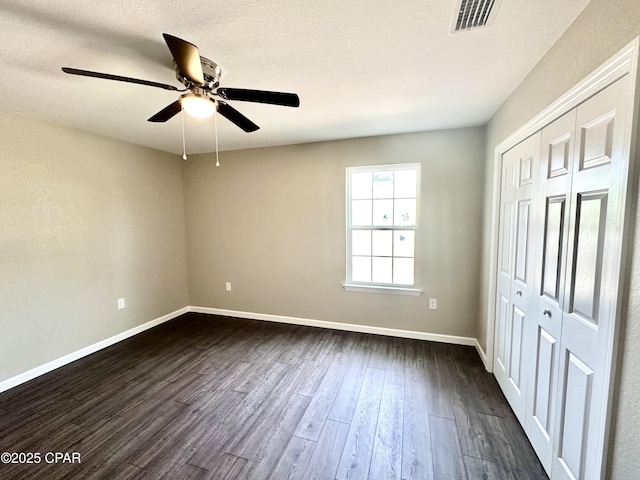 unfurnished bedroom with ceiling fan, dark hardwood / wood-style flooring, a closet, and a textured ceiling