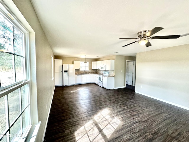 unfurnished living room with plenty of natural light, dark wood-type flooring, sink, and ceiling fan