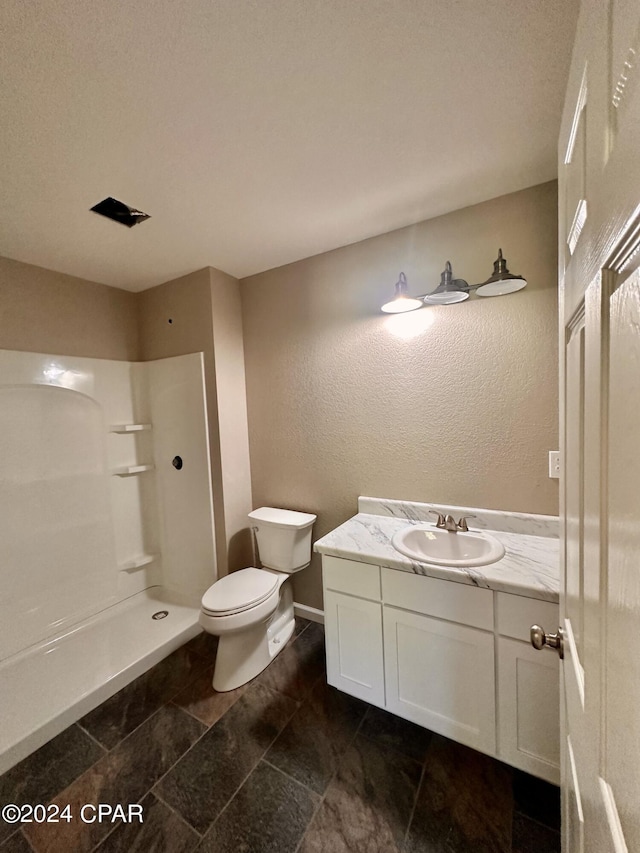 bathroom featuring vanity, a shower, and toilet