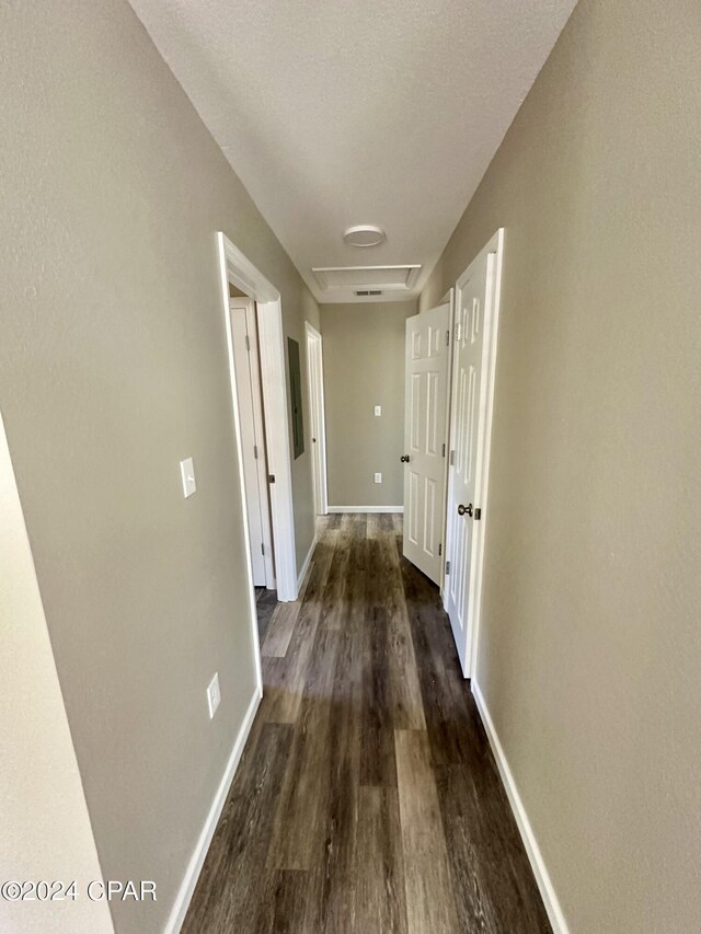 corridor with dark hardwood / wood-style flooring and a textured ceiling