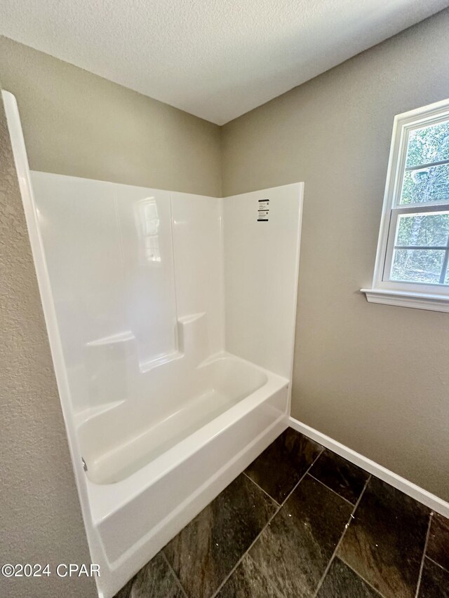 bathroom with a textured ceiling, tile patterned floors, and  shower combination