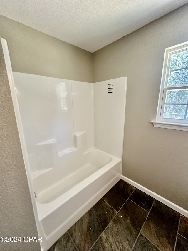 bathroom with shower / bath combination and a textured ceiling