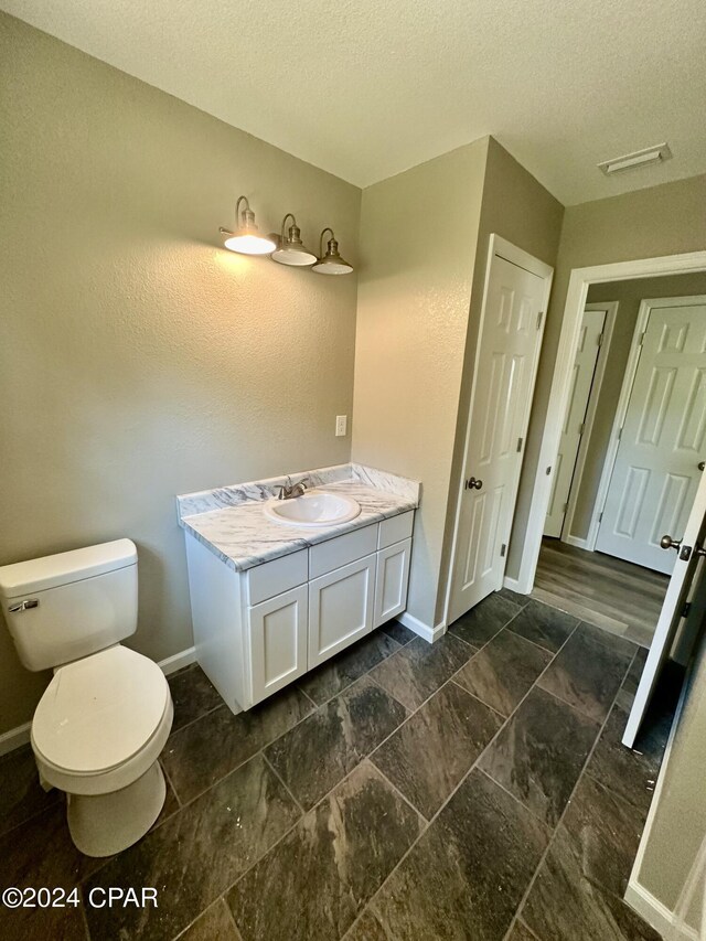 bathroom featuring vanity, a textured ceiling, and toilet