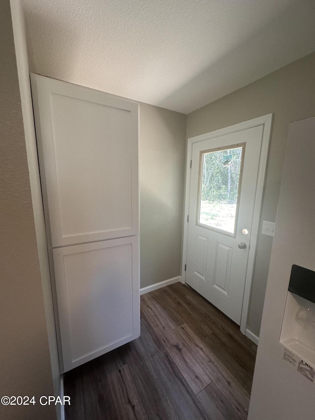 doorway with dark hardwood / wood-style floors and a textured ceiling