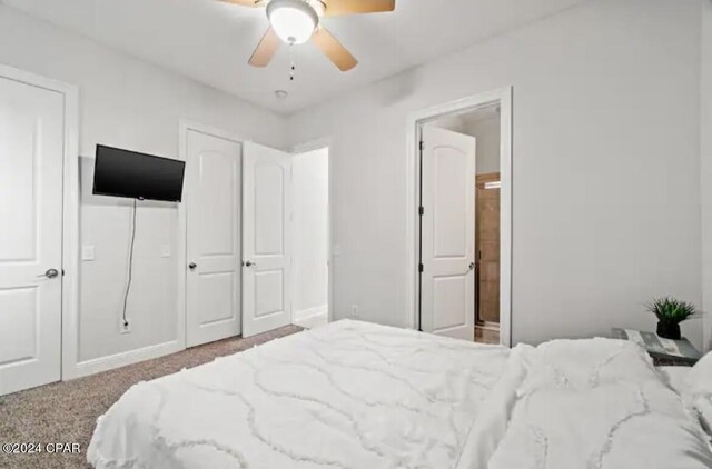 bedroom with ceiling fan, ensuite bath, and carpet flooring