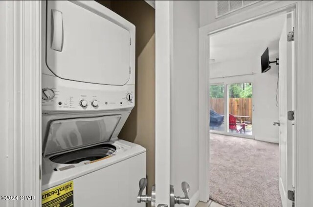 clothes washing area with stacked washer / dryer and light colored carpet