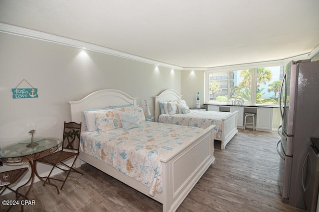 bedroom featuring hardwood / wood-style floors, stainless steel fridge, and ornamental molding