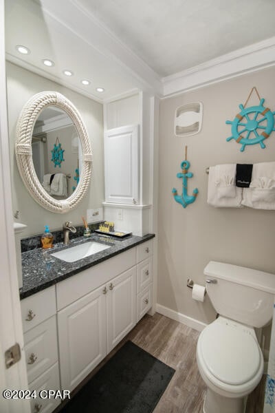 bathroom featuring wood-type flooring, toilet, vanity, and ornamental molding