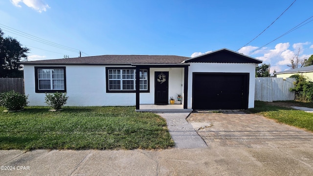 ranch-style house featuring a garage, fence, decorative driveway, stucco siding, and a front lawn