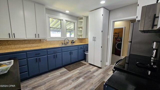 kitchen featuring sink, decorative backsplash, blue cabinets, and light hardwood / wood-style flooring