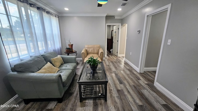 living room with arched walkways, dark wood-style flooring, visible vents, baseboards, and ornamental molding