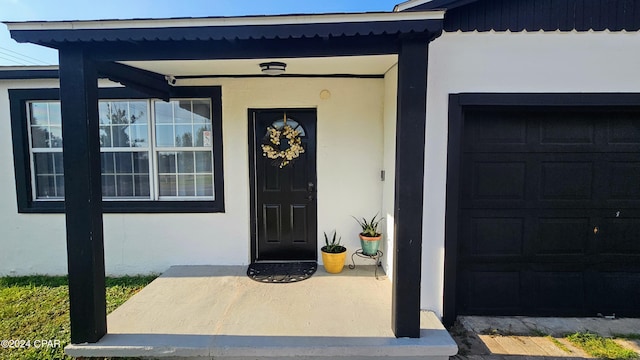 entrance to property featuring a porch and a garage