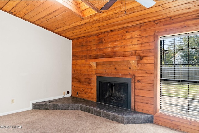 unfurnished living room with a tile fireplace, beam ceiling, wood walls, carpet, and wooden ceiling