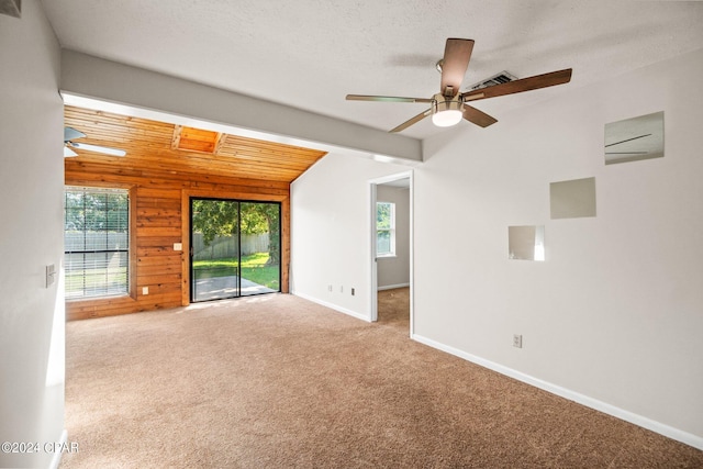 empty room featuring ceiling fan, wood ceiling, a textured ceiling, wooden walls, and carpet