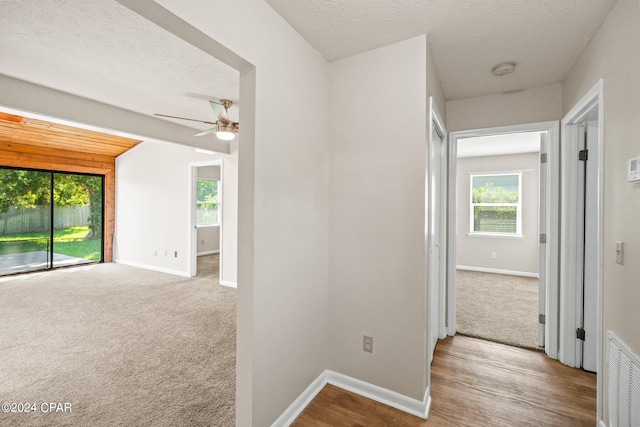 hallway with light wood-type flooring and a textured ceiling