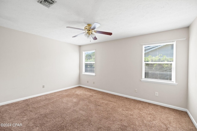 carpeted empty room with ceiling fan and a textured ceiling