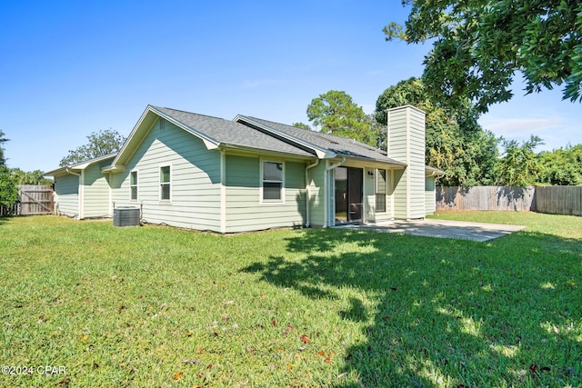 rear view of property with cooling unit, a patio area, and a yard