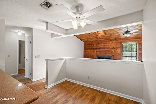 unfurnished room featuring a textured ceiling, wood walls, ceiling fan, and hardwood / wood-style flooring