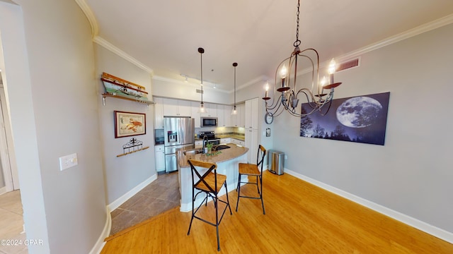 dining room with an inviting chandelier, light hardwood / wood-style flooring, and crown molding