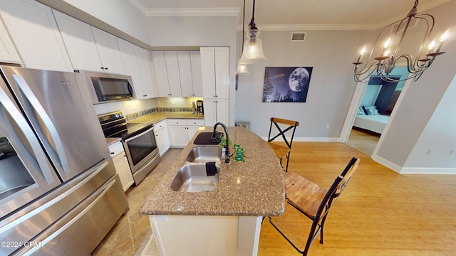 kitchen with stainless steel appliances, light hardwood / wood-style floors, stone counters, a center island with sink, and white cabinets