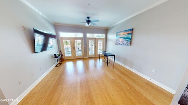 empty room featuring ceiling fan, light hardwood / wood-style floors, ornamental molding, and french doors