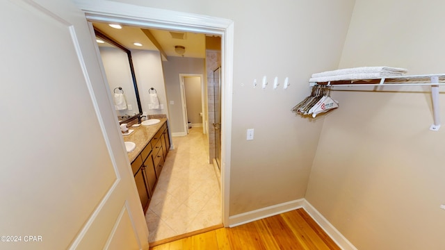 bathroom featuring a shower with door, dual bowl vanity, and hardwood / wood-style flooring