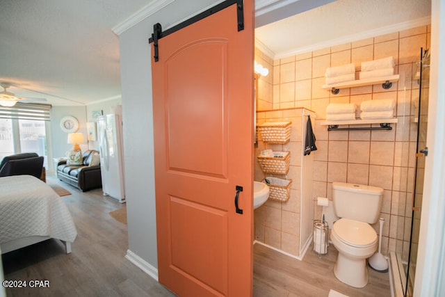 bathroom with tile walls, toilet, hardwood / wood-style flooring, and crown molding