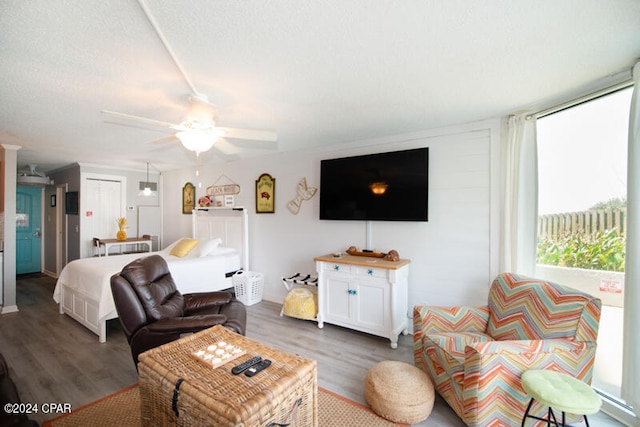 living room with a textured ceiling, ceiling fan, and dark hardwood / wood-style flooring