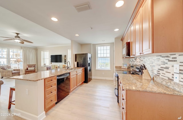 kitchen featuring a wealth of natural light, appliances with stainless steel finishes, light hardwood / wood-style flooring, and light stone counters