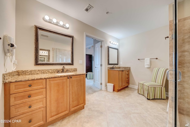 bathroom with a shower with door, tile patterned flooring, and vanity