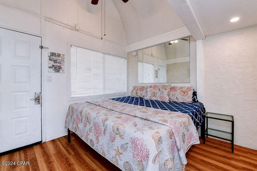 bedroom with ceiling fan, vaulted ceiling, and hardwood / wood-style flooring