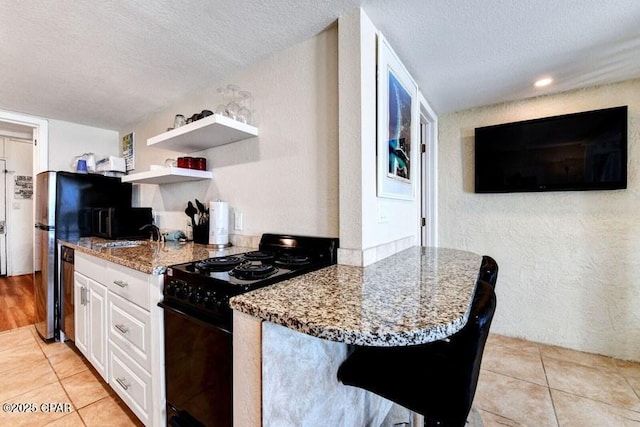 kitchen with white cabinetry, black range with electric cooktop, stone countertops, and a textured ceiling