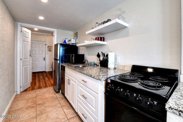 kitchen featuring black range with electric cooktop, light tile patterned floors, light stone countertops, and white cabinets