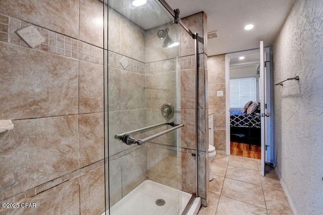 bathroom with a shower with shower door, toilet, and tile patterned flooring