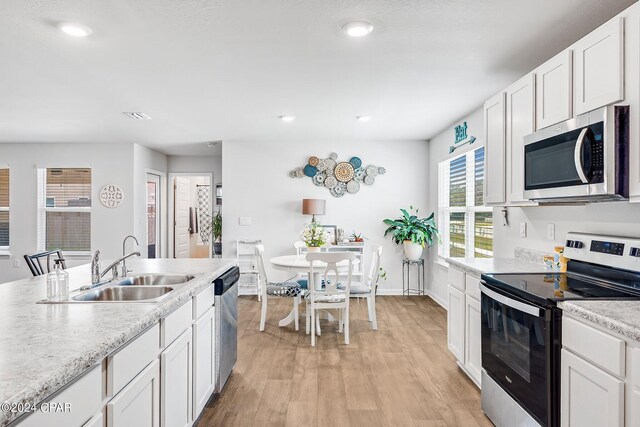 kitchen featuring light wood-type flooring, sink, stainless steel appliances, and white cabinetry