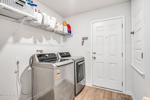 clothes washing area featuring washer and dryer and light hardwood / wood-style flooring